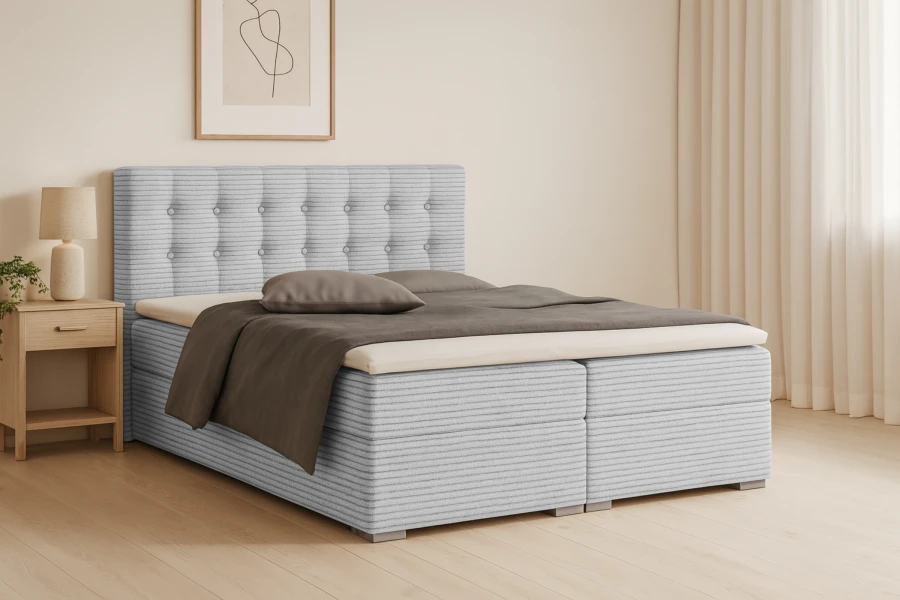 Zeitloses Boxspringbett in Hellgrau mit Cord-Struktur und gepolstertem Kopfteil.