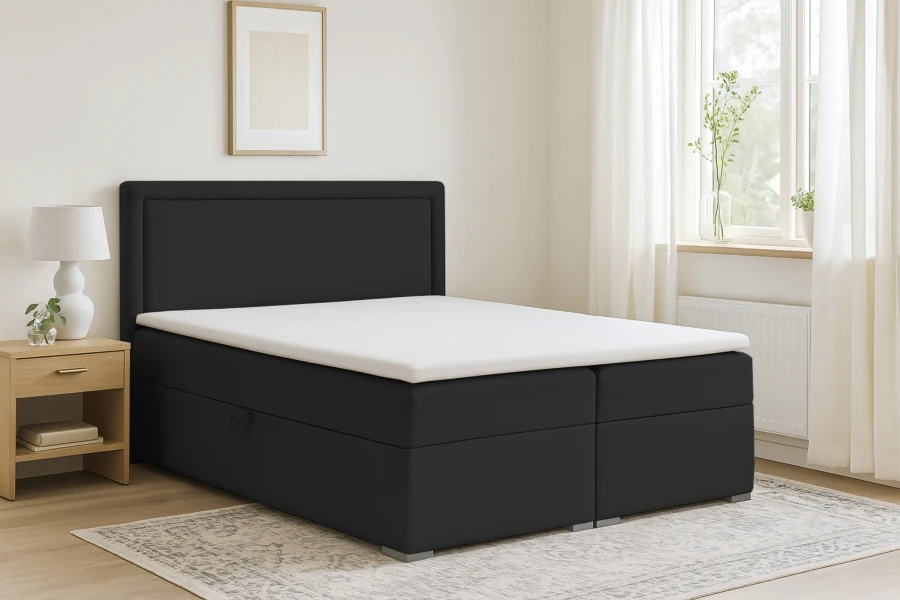 Dunkelgraues Boxspringbett im hellen Schlafzimmer mit Nachttisch und Teppich.