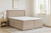 Beiges Boxspringbett im hellen Schlafzimmer mit stilvoller Dekoration und Teppich.