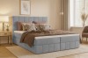 Hellgraues Boho Boxspringbett mit vertikaler Steppung in wohnlichem Ambiente.