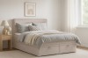 Beige Boxspringbett mit Stauraum in einem hell eingerichteten Schlafzimmer.