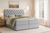 Gezellige slaapkamer met lichtgrijs boxspringbed, nachtkastje en moderne wanddecoratie.