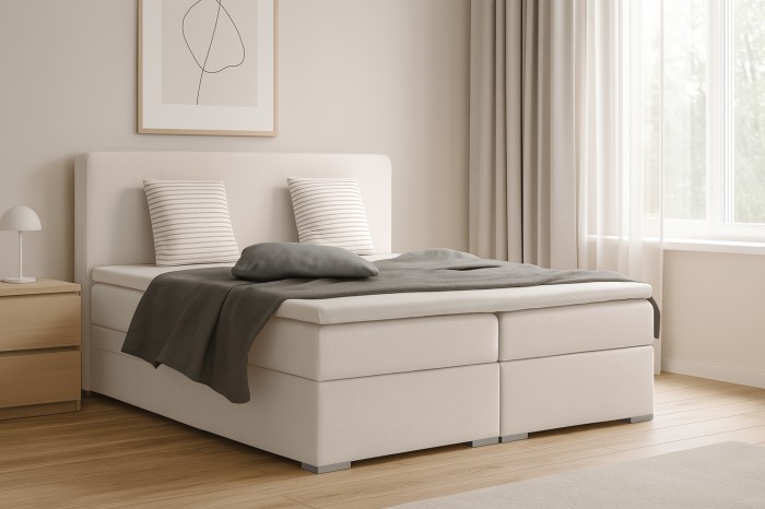 Beige boxspringbed in lichte slaapkamer naast raam
