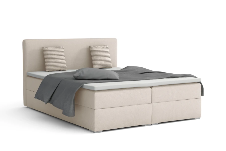 Elegant boxspringbed Bello in crème met decoratieve kussens en grijze sprei vrijstaand.