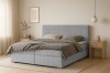 Hellblaues Boxspringbett mit Kopfteil in gemütlichem Schlafzimmer-Ambiente.