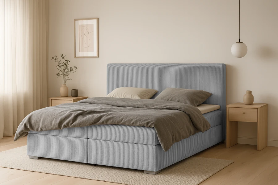 Hellblaues Boxspringbett mit Kopfteil in gemütlichem Schlafzimmer-Ambiente.