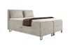 Beiges Boxspringbett in Cord-Optik mit Kissen und dekorativer brauner Decke.