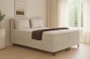 Beiges Boxspringbett mit Bettkasten und Kopfteil in modernem Schlafzimmer.