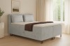 Modernes Boxspringbett in Hellgrau mit Bettkasten im hellen Schlafzimmer.