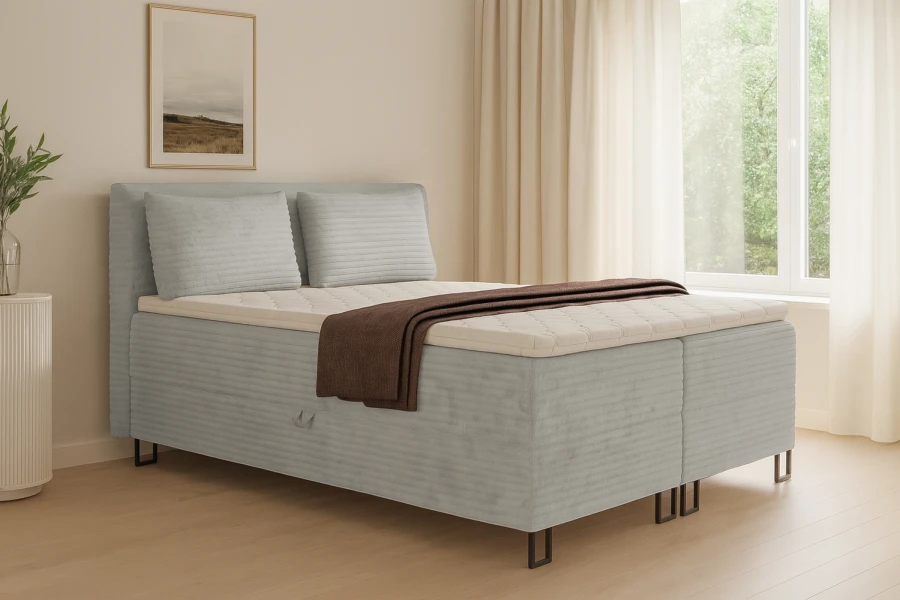 Modernes Boxspringbett in Hellgrau mit Bettkasten im hellen Schlafzimmer.