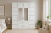 Großer weißer Kleiderschrank mit Spiegeltüren und Aufsatzschrank im hellen Schlafzimmer.