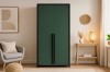 Eleganter grüner Kleiderschrank mit schwarzen Metallgriffen in einem hellen Wohnraum.