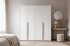 Moderner weißer Kleiderschrank mit silbernen Griffen in einem hellen, minimalistischen Schlafzimmer.