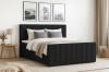 Schwarzes Boxspringbett in einem hell eingerichteten Schlafzimmer.