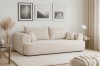 Minimalistisches beige Sofa in hellem Wohnzimmer mit Wandbildern und Pampasgras.