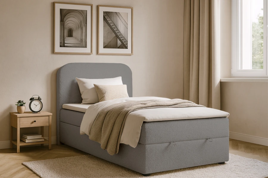 Graues Boxspringbett mit gepolstertem Kopfteil in modernem Schlafzimmer-Ambiente.