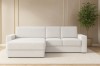 Weißes Bouclé-Ecksofa in hellem Wohnzimmer mit Pflanze.