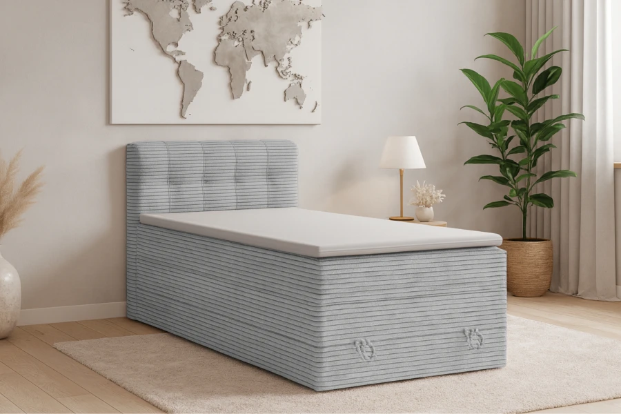 Graues Einzel-Boxspringbett in Cord-Optik im hellen Schlafzimmer-Ambiente.