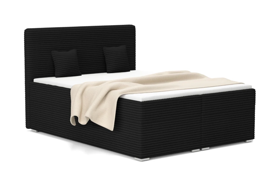 Schwarzes Boxspringbett in Cord-Optik mit beiger Decke auf weißem Hintergrund.