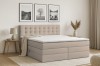 Beiges Boxspringbett mit gestepptem Kopfteil in einem hellen, modern eingerichteten Schlafzimmer.