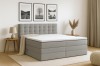 Graues Boxspringbett in modern eingerichtetem Schlafzimmer mit Wandbildern und Holztisch.