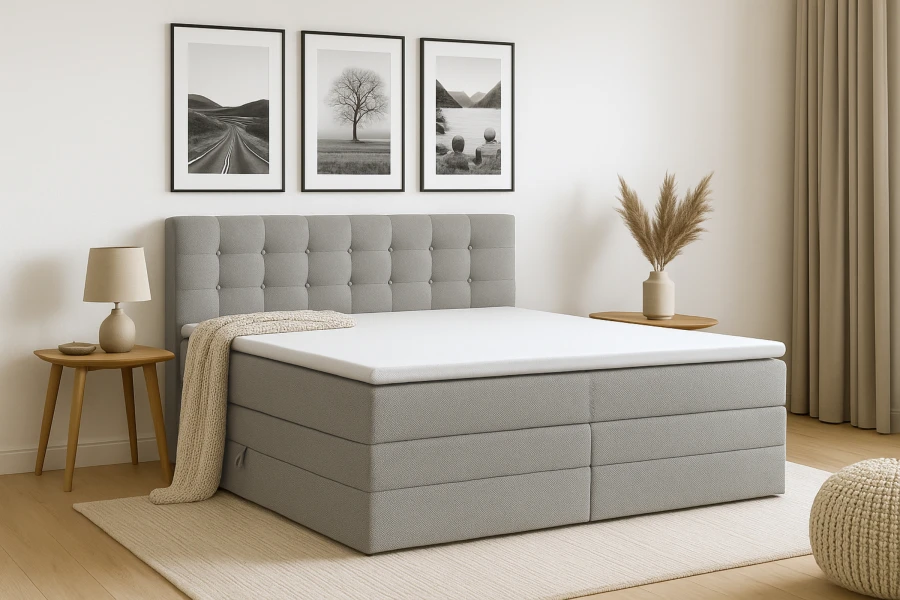 Graues Boxspringbett in modern eingerichtetem Schlafzimmer mit Wandbildern und Holztisch.