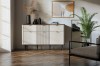 Helles Wohnzimmer mit elegantem weißem Sideboard, Wandbild und Zimmerpflanze auf Parkettboden.