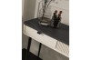 Detailansicht eines beigen Schminktischs mit dunkler Marmor-Oberfläche und dekorativem Riffel-Design.