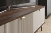 Detail eines TV-Lowboards in Nussbaum-Optik mit beigen Fronten, Rillenstruktur und Goldgriffen.