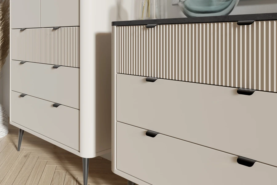 Nahaufnahme von beigen Kommodenschubladen mit Rillenstruktur und eleganten schwarzen Griffen.