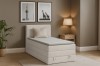Beiges Boxspringbett im Schlafzimmer-Ambiente mit Lampe und Zimmerpflanze