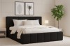 Modernes schwarzes Designerbett im Schlafzimmer mit Wandbildern, Pflanze und Nachttisch.