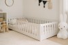 Weißes Kinderbett mit Rausfallschutz im skandinavisch eingerichteten Kinderzimmer.
