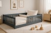 Modernes Kinderbett in Grau im skandinavisch eingerichteten Kinderzimmer mit Teppich und Holzspielzeug.