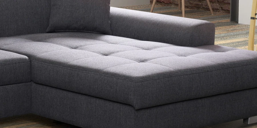 Detailansicht der gesteppten Sitzfläche eines grauen Stoffsofas.