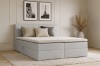 Modernes hellgraues Boxspringbett Lina mit Kissen im Schlafzimmer.