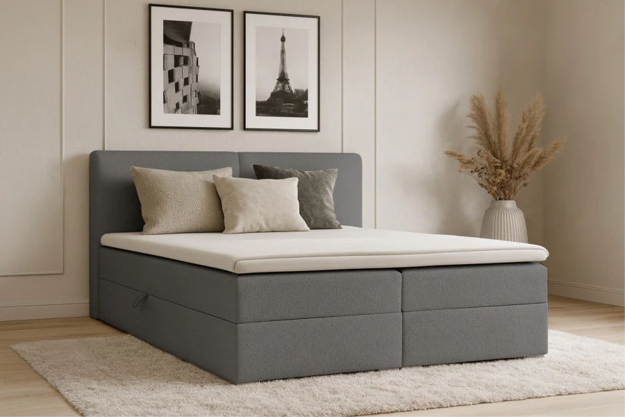 Modernes graues Boxspringbett im hellen Schlafzimmer mit dekorativen Kissen und Teppich.
