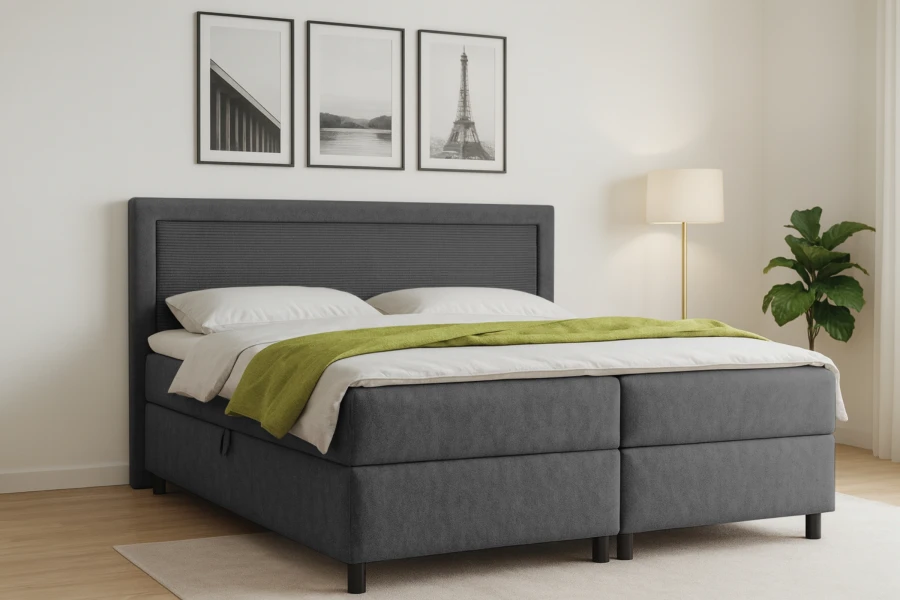 Stilvolles Schlafzimmer mit grauem Boxspringbett, Wandbildern und Zimmerpflanze.