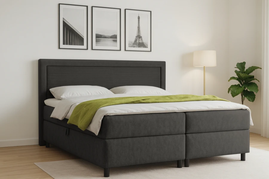Modernes Boxspringbett in Anthrazit mit grüner Tagesdecke im hellen Schlafzimmer.