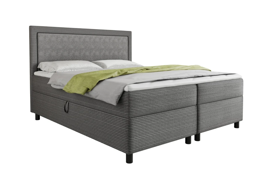 Boxspringbett in hellem Grau mit Cord-Bezug und grünem Plaid