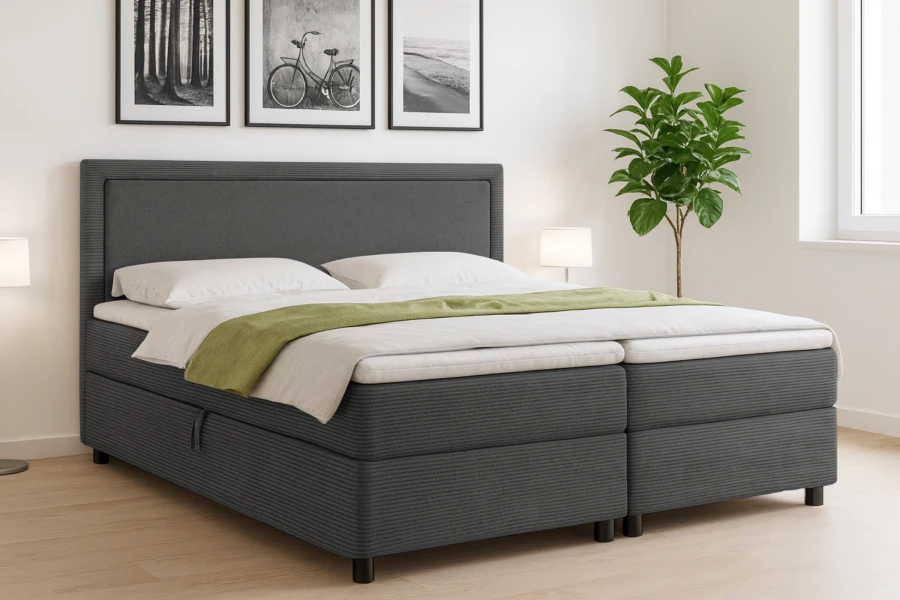 Graues Boxspringbett mit Stauraum und dekorativer grüner Tagesdecke.