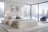 Hell eingerichtetes Schlafzimmer mit Bouclé-Bett und großem Fenster zur Winterlandschaft.