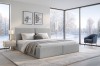 Modernes Schlafzimmer Design mit hellgrauem Bett und großem Fenster zur Winterlandschaft.