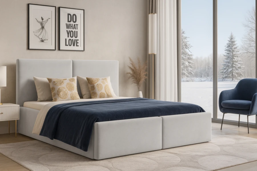 Gemütliches Schlafzimmer mit hellem Polsterbett, blauem Sessel und Blick auf eine Winterlandschaft.