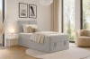 Modernes Schlafzimmer mit grauem Boxspringbett, hellem Teppich und stilvoller Einrichtung