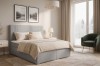 Modernes Schlafzimmer-Ambiente mit grauem Boxspringbett, hellem Teppich und Natur-Ausblick.