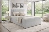 Modernes hellgraues Boxspringbett in einem hellen Schlafzimmer mit Gartenblick.