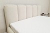 Weiße Matratze auf einem modernen Polsterbett mit weichem Kopfteil in einem hellen Schlafzimmer.