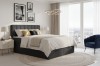 Dunkelgraues Boxspringbett David mit Stauraum-Bettkasten in modernem Zimmer mit City-Aussicht.