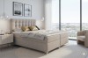 Beiges Boxspringbett in modernem Schlafzimmer mit großen Fenstern und Stadtblick.